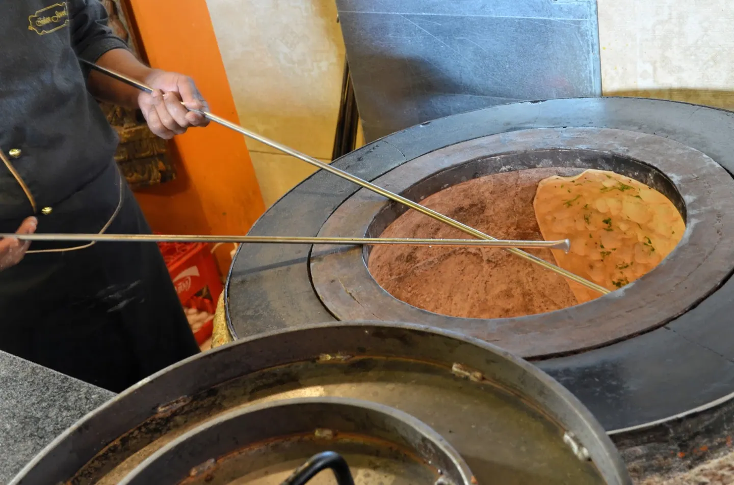 A chef pulling fresh naan from the clay tandoor at Indian Jewel, Prague